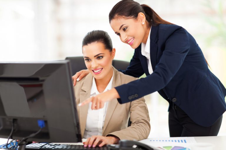 cheerful two business women working at the office on a computer